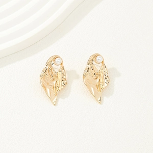 Close-up of irregular gold alloy earrings with white pearls and textured surface