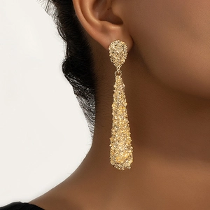 Long golden waterdrop earrings with irregular hammered texture on model