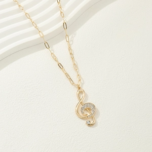 Golden treble clef pendant necklace with sparkling crystals on a long link chain