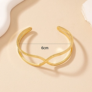 Detail view of golden geometric cross bracelet showing 6cm inner diameter and open cuff design