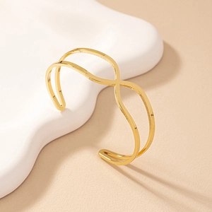 Minimalist gold crisscross wave open bangle featuring a modern geometric double-line design