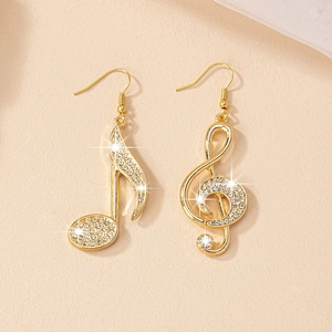 Detailed macro of asymmetric gold musical note earrings with sparkling pavé rhinestones