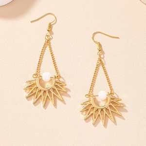 Close-up of golden bohemian sun drop earrings with white beads and triangular chain link