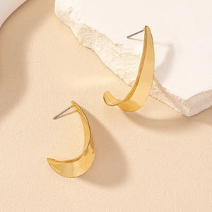 Minimalist gold geometric curved earrings displayed on a natural stone background