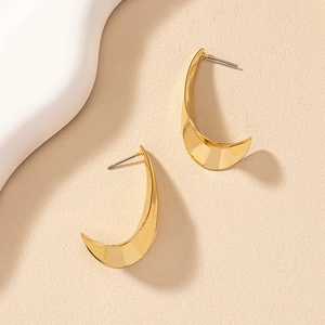 Minimalist geometric gold crescent earrings on a textured beige display stand