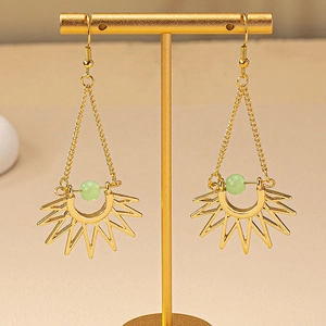 Detail of bohemian sunburst drop earrings featuring gold chains and green gemstone beads