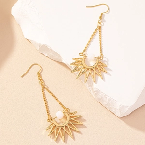 Bohemian gold sun drop earrings with white beads on a natural stone display