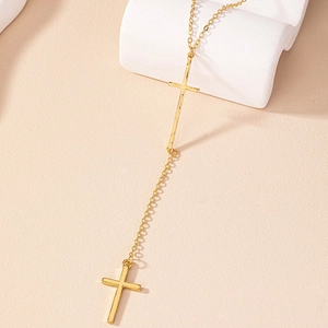 Elegant gold double cross Y-shaped necklace with long tassel chain on a display stand