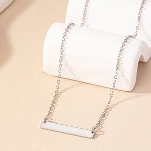 Collier minimaliste argenté avec pendentif rectangulaire sur présentoir blanc ondulé