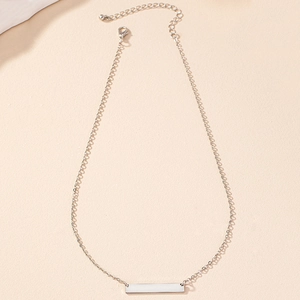 Collier minimaliste argenté avec pendentif rectangulaire et chaîne réglable sur fond beige