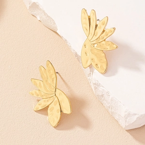 Asymmetric golden flower stud earrings with hammered metal texture on white stone base