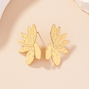 Golden flower earrings with hammered metal texture displayed on a minimalist background