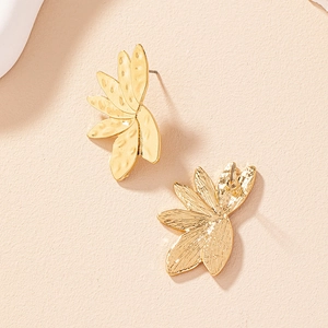 Detailed close-up of golden leaf earrings with handmade hammered metal texture and stud back