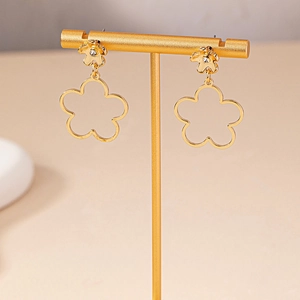 Elegant gold hollow flower earrings with sparkling rhinestones on a jewelry display stand