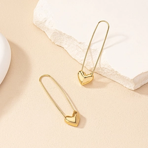 Minimalist gold paperclip heart earrings displayed on a white textured stone background