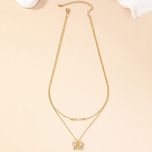 Close-up of double-layer gold necklace with rhinestone bow pendant and bar detail
