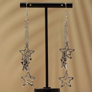 French vintage silver star tassel earrings with long metallic fringe on display stand