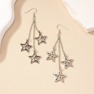 Detail view of retro silver star tassel earrings with long chain fringe on a stone prop