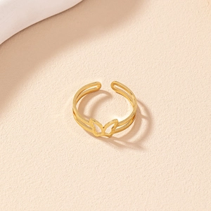 Close-up of golden hollow butterfly open ring with double-layered band on beige surface