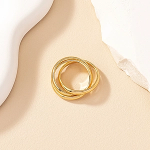 Minimalist multi-layered interlocking gold rings displayed on elegant beige textured stone