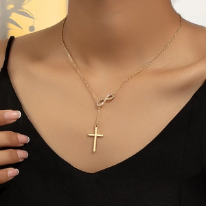 Collana dorata con pendente infinito e croce con diamanti indossata da una modella
