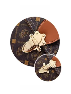 Detail of gold metal buckle on brown monogram shoulder bag with neat white stitching