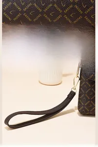 Détail de la sacoche en cuir marron avec imprimé lettres et fermoir en métal doré