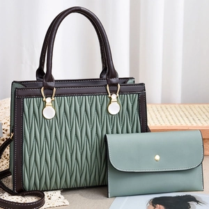 Detail of contrast stitch handbag with wave quilting and matching clutch on wooden tray