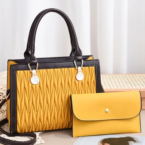 Detail of yellow pleated handbag set with dark brown handles and golden hardware accents