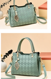 Detail of light green rhombus embossed handbag with gold leaf charm and adjustable strap
