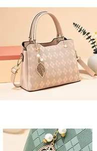 Detail of diamond-embossed tote bag with leaf pendant and pearl charm in cream and sage green
