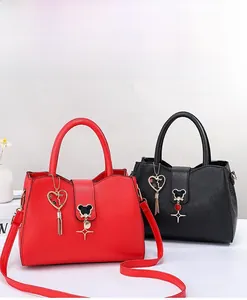 Close-up of red and black lychee texture handbags with heart tassels and metal bear buckles