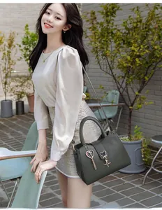 Dark gray faux leather crossbody bag with heart pendant shown on model in street scene
