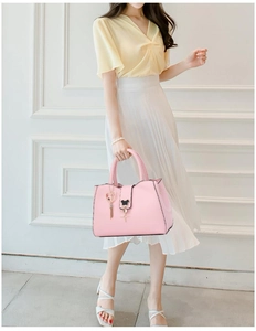 Pink crossbody bag with heart tassel and bear charm detail on elegant interior background