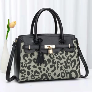 Detail of luxury cow print handbag with gold padlock and stylish leather stitching