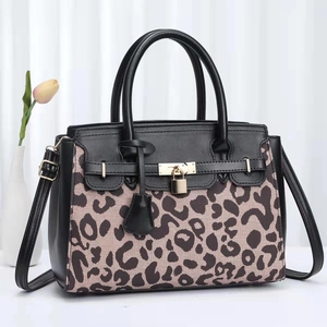 Fashionable leopard print handbag with black handles and metal lock detail on white background