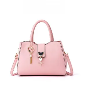 Pink textured leather shoulder bag featuring a bear-shaped lock and heart tassel detail