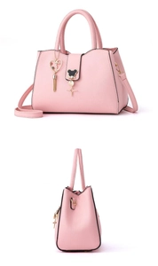 Detail view of pink pebbled leather handbag with detachable strap and heart metal charms