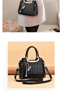 Detail of black woven texture handbag with golden handle and floral charm accessory