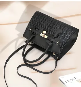 Détail du sac à main noir en cuir tressé avec cadenas métallique et breloque clé