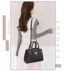 Détail du sac à main noir à texture tissée avec cadenas doré et bandoulière chic