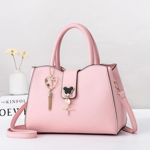 Pink minimalist tote bag with tassel charm and adjustable strap on a white background