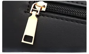 Détail de la fermeture éclair dorée polie et du cuir noir texturé du grand sac à main