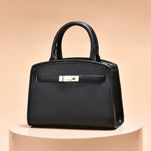 Sac à main structuré en cuir noir avec fermoir doré sur socle beige élégant