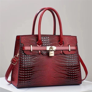Macro view of burgundy lizard pattern leather with golden padlock hardware detail