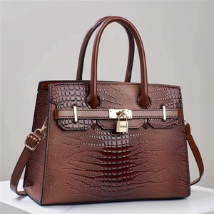 Brown lizard embossed tote bag with double handles and metal lock detail on white podium