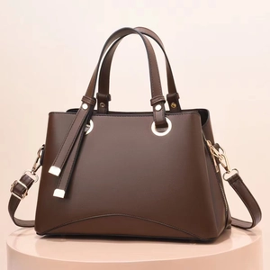 Dettaglio di borsa in pelle marrone scuro con finiture dorate e tracolla regolabile