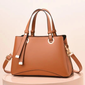 Dettaglio della borsa tote in pelle marrone con finiture dorate e cerniera laterale