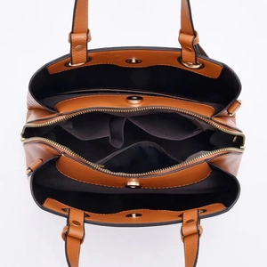 Dettaglio interno della borsa in pelle marrone con tre scomparti e chiusure magnetiche