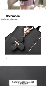 Detalle de bolso negro de cuero sintético con colgante de flor y cadena de metal dorado